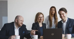 en grupp tittar på en datorskärm och en kille pekar på något