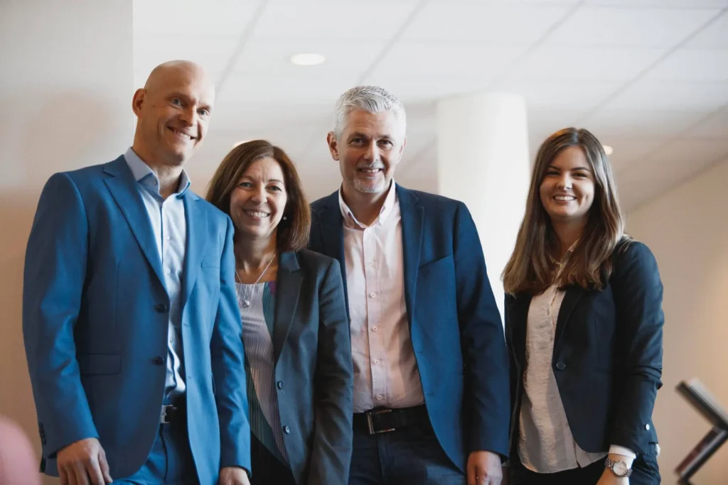 en ledningsgrupp poserar framför kameran. två män och två kvinnor