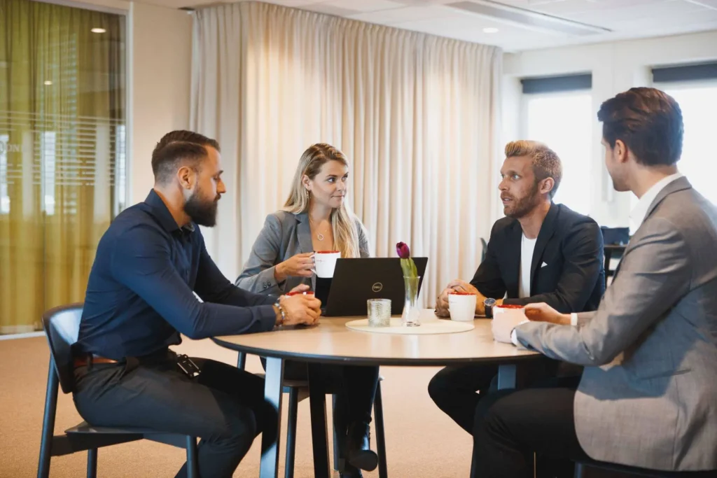 fyra människor sitter runt ett bord och diskuterar