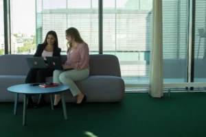 två personer sitter i en soffa och kollar i en laptop